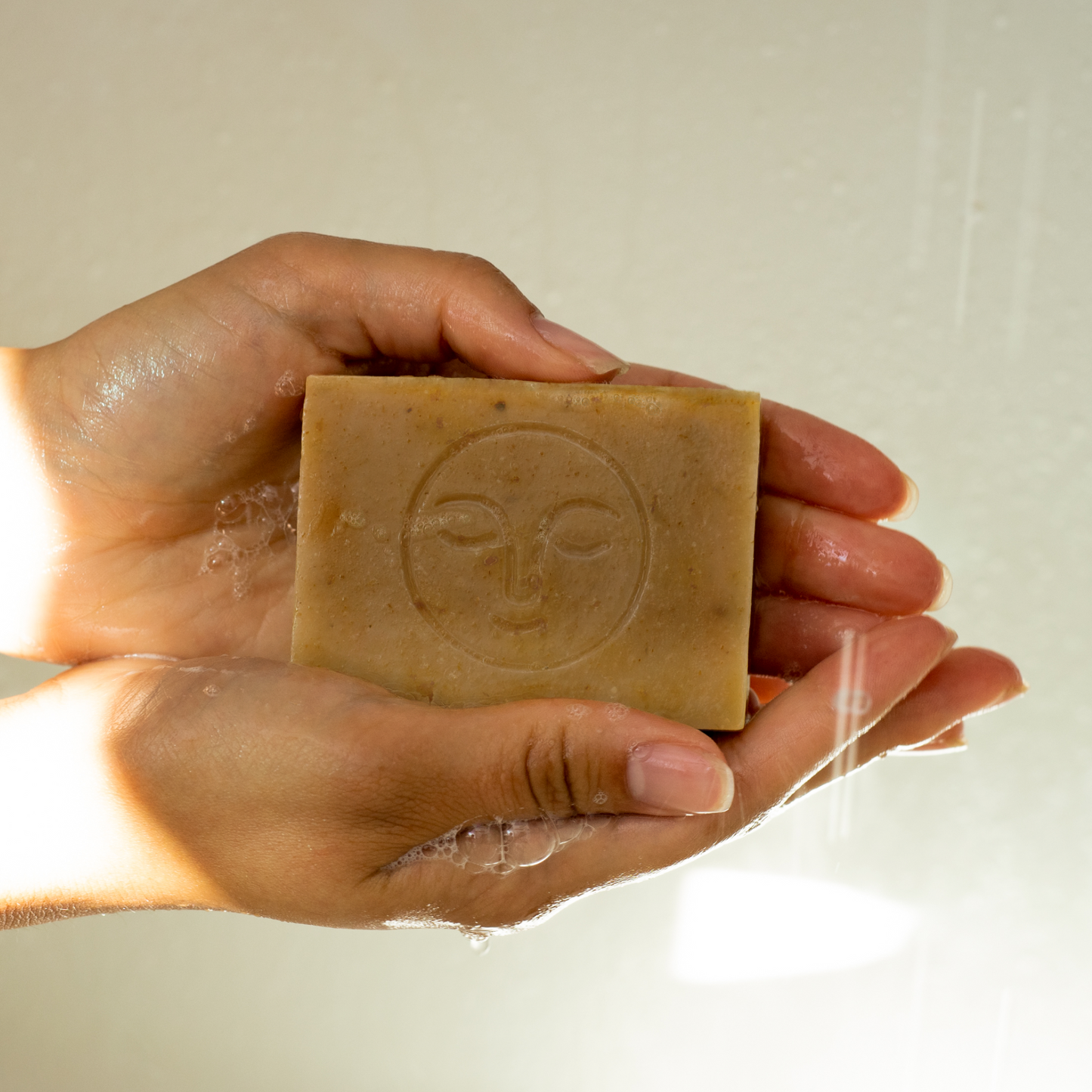 Moon Valley Organics Herbal Soap Bar Lavender Ingredients and Hands holding a lathered bar of soap under shower